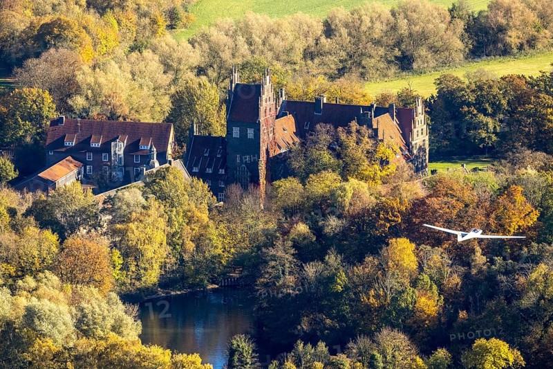 Aerial photo, motor glider at Heessen Castle in the autumnal forest in the Heessen district of Hamm, Ruhr area, North Rhine-Westphalia, Germany, education, educational institution, castle, DE, Europe, aircraft, Hamm, autumn colours, educational institute, aerial photo, aerial photography, aerial photography, motor glider, castle, castle complex, school, overview, bird's-eye view, overview