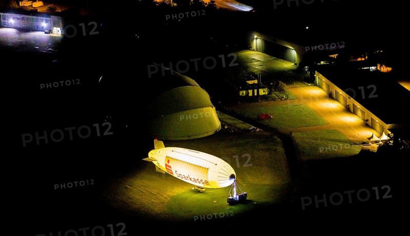 Aerial photograph, Sparkasse airship, airfield Essen Mülheim, Haarzopf, Essen, Ruhr area, North Rhine-Westphalia, Germany, outdoor lighting, DE, twilight, Europe, flying objects, light pollution, aerial photograph, aerial photography, aviation, aerial photography, airship, night aerial photograph, streetlights, street lamps, overview, bird's eye view, zeppelin, illuminated, illuminated houses, illuminated house, birds-eyes view, artificial light, night, nightflight, overview