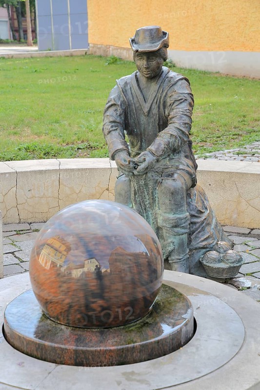 Monument to founder David Strickermann, town history on the development of the textile industry, seated male figure with tub and ball of wool, symbols, wool, ball, bronze sculpture, modern art, rotating granite ball, stone ball, fountain, Strickermannbrunnen, Schulplatz, Apolda, Thuringia, Germany