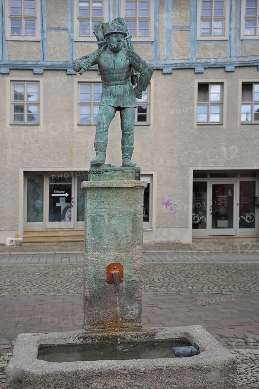 Wood carrier by Bernhard Frydag, 1914, male figure carrying basket with wood on his back, symbol for forestry, logging, lumberjack, wood, fountain, wood carrier fountain, wood market, Aschersleben, Harz, Saxony-Anhalt, Germany