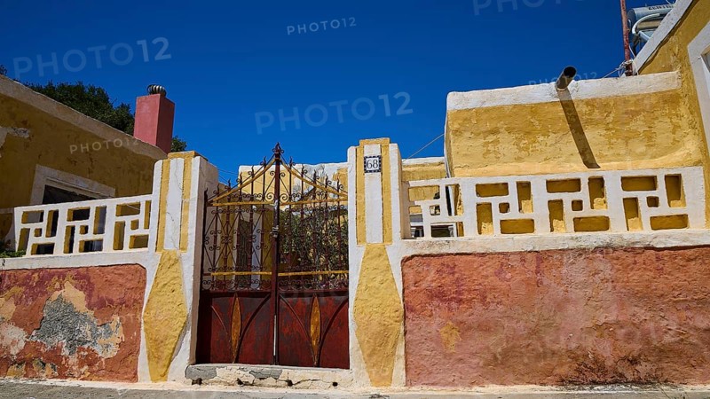 A yellow rustic building with a metallic Tor tor under a blue sky, Kattavia village, southern tip of Rhodes, Rhodes, Dodecanese, Greek Islands, Greece