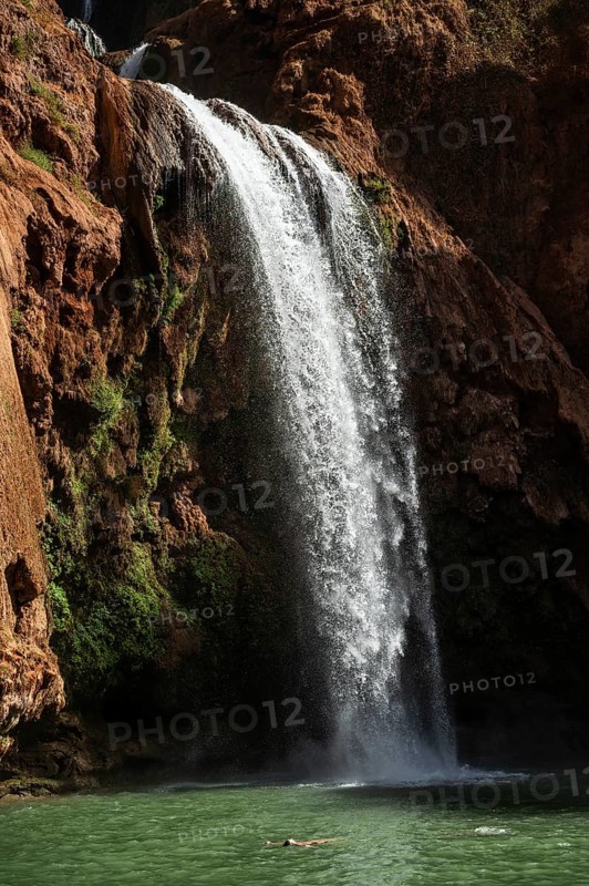 Relaxed woman floats on his back under beautiful Ouzoud waterffall in Morocco