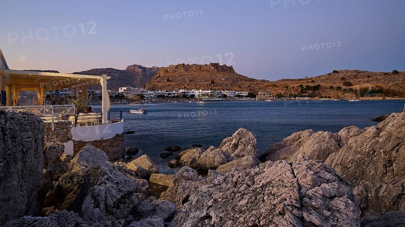 Restaurant Argo, Rock-framed view of a coastal town and sea at dusk, bay, Feraklos fortress, Charaki, Haraki, east coast of Rhodes, Rhodes, Dodecanese, Greek Islands, Greece