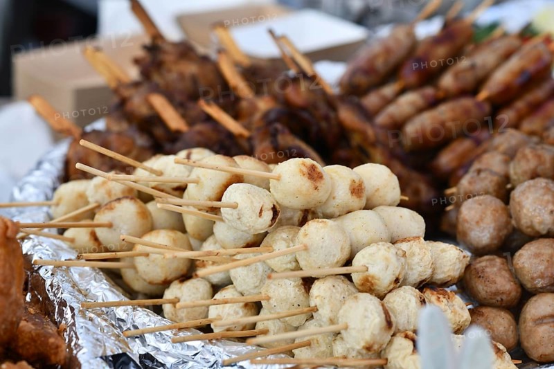 Close up of white Thai fish or chicken meat balls grilled skewers at street food market