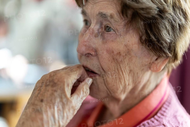 Close-up, authentic, unposed portrait of a 90+ year old senior woman with dementia and Alzheimer's disease in a retirement home, holding a hand to her face, Cologne, North Rhine-Westphalia, Germany