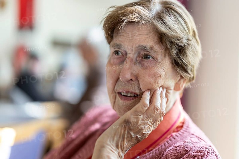 Close-up, authentic, unposed portrait of a 90+ year old senior woman with dementia and Alzheimer's disease in a retirement home, holding a hand to her face, Cologne, North Rhine-Westphalia, Germany