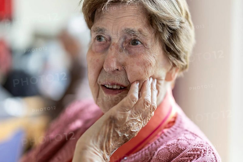 Close-up, authentic, unposed portrait of a 90+ year old senior woman with dementia and Alzheimer's disease in a retirement home, holding a hand to her face, Cologne, North Rhine-Westphalia, Germany