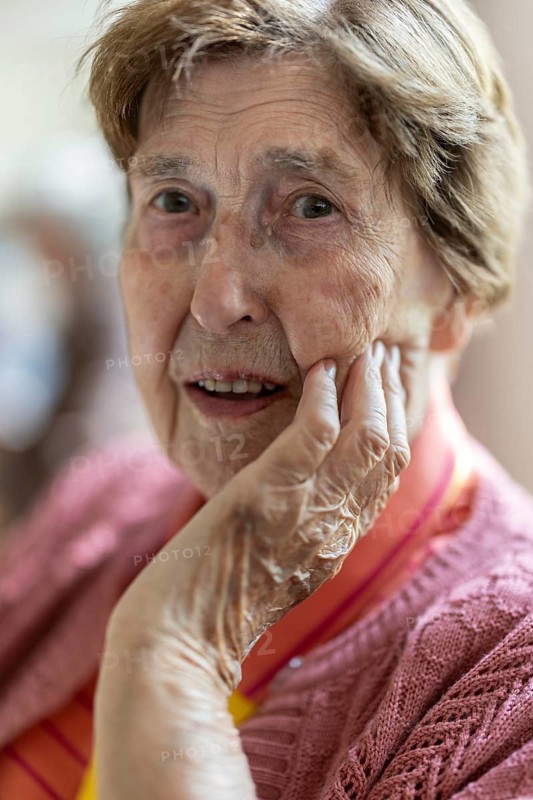 Close-up, authentic, unposed portrait of a 90+ year old senior woman with dementia and Alzheimer's disease in a retirement home, holding a hand to her face, Cologne, North Rhine-Westphalia, Germany
