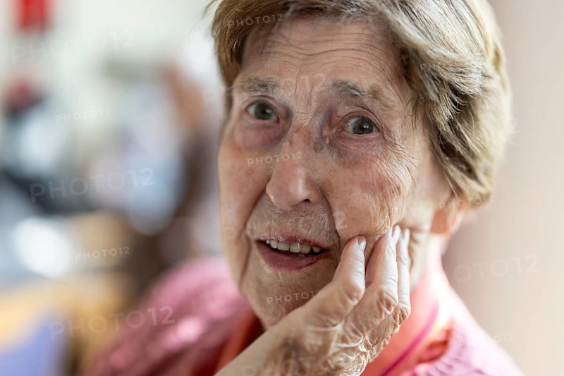 Close-up, authentic, unposed portrait of a 90+ year old senior woman with dementia and Alzheimer's disease in a retirement home, holding a hand to her face, Cologne, North Rhine-Westphalia, Germany