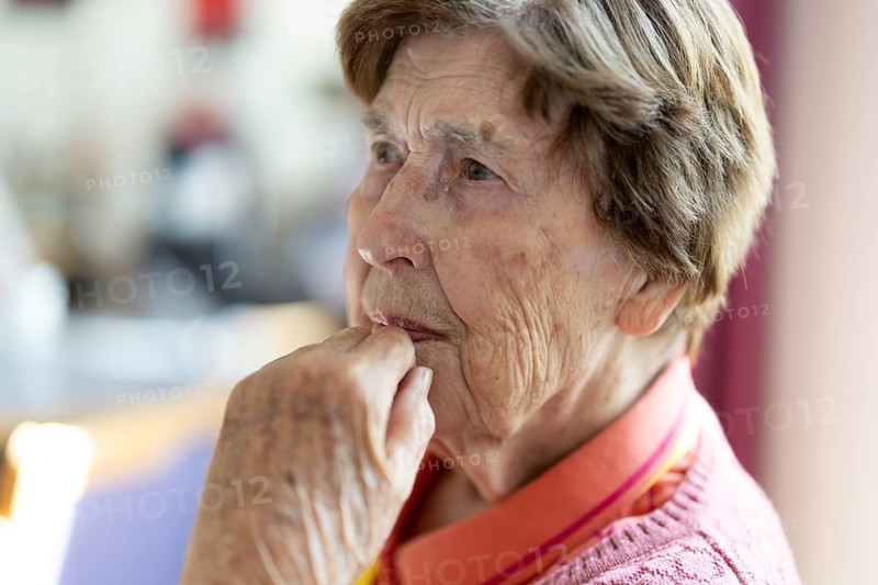 Close-up, authentic, unposed portrait of a 90+ year old senior woman with dementia and Alzheimer's disease in a retirement home, holding a hand to her face, Cologne, North Rhine-Westphalia, Germany
