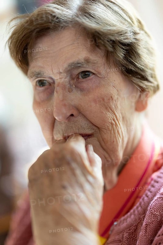 Close-up, authentic, unposed portrait of a 90+ year old senior woman with dementia and Alzheimer's disease in a retirement home, holding a hand to her face, Cologne, North Rhine-Westphalia, Germany