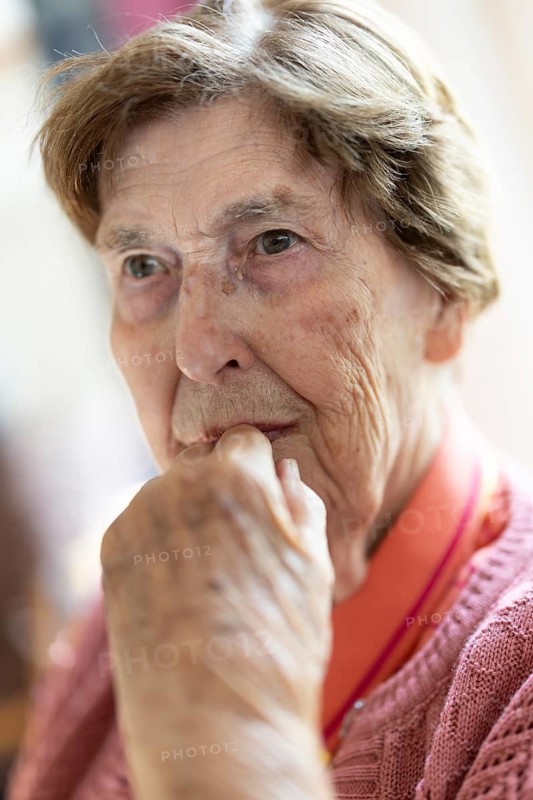 Close-up, authentic, unposed portrait of a 90+ year old senior woman with dementia and Alzheimer's disease in a retirement home, holding a hand to her face, Cologne, North Rhine-Westphalia, Germany