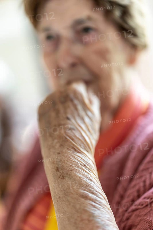 Close-up, authentic, unposed portrait of a 90+ year old senior woman with dementia and Alzheimer's disease in a retirement home, holding a hand to her face, Cologne, North Rhine-Westphalia, Germany