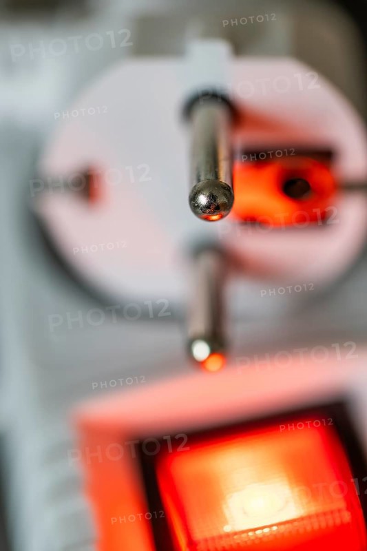 Close-up of a white power plug, Schuko plug, on a multiple socket with red indicator light, symbolic image for electricity, electrical energy, power consumption, studio shot, Germany