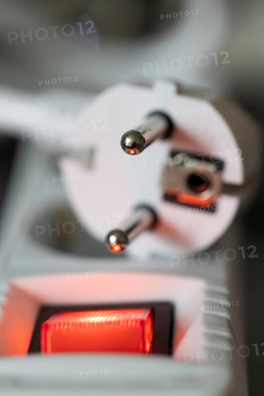 Close-up of a white power plug, Schuko plug, on a multiple socket with red indicator light, symbolic image for electricity, electrical energy, power consumption, studio shot, Germany