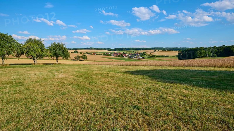 Rural scene with a view of a village and surrounding fields under a blue sky, Reichartshausen, Amorbach, Odenwald, Bavaria, Germany