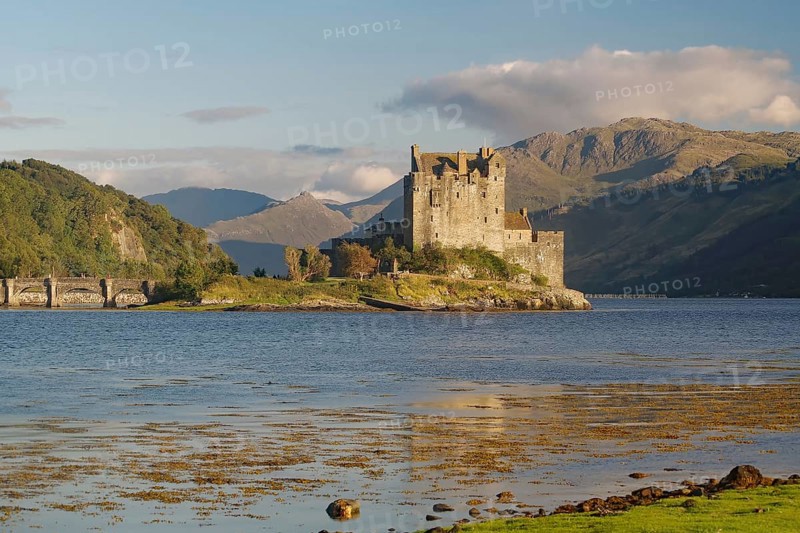 A picturesque castle on an island in the water, surrounded by mountains and a slightly cloudy sky, with dramatic mountains in the background, Eilean Donan Castle, Highlander, film set, Scotland, Great Britain