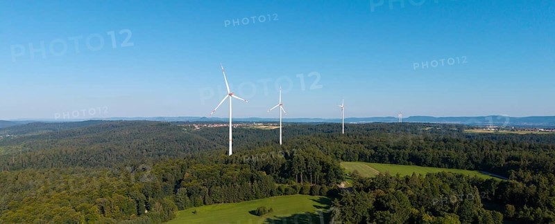 Wind turbines stand above a wooded hill under a clear blue sky, near Schorndorf, Rems Valley, Baden-Württemberg, Germany