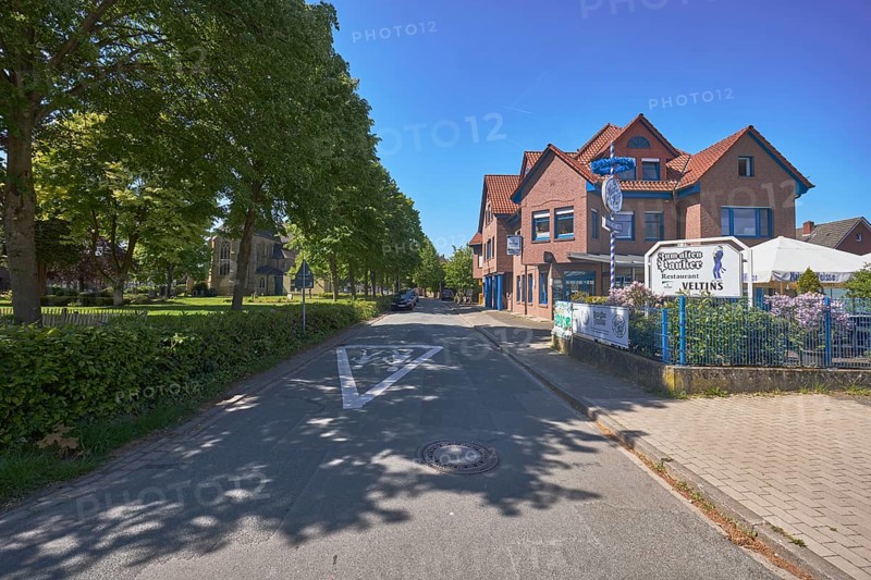 Restaurant Zum alten Pauker, clinker brick building, general development, historic cemetery, trees, lawn, road, road marking Attention children, blue sky, cloudless, Alte Schulstraße, Alfhausen, district of Osnabrück, Lower Saxony, Germany