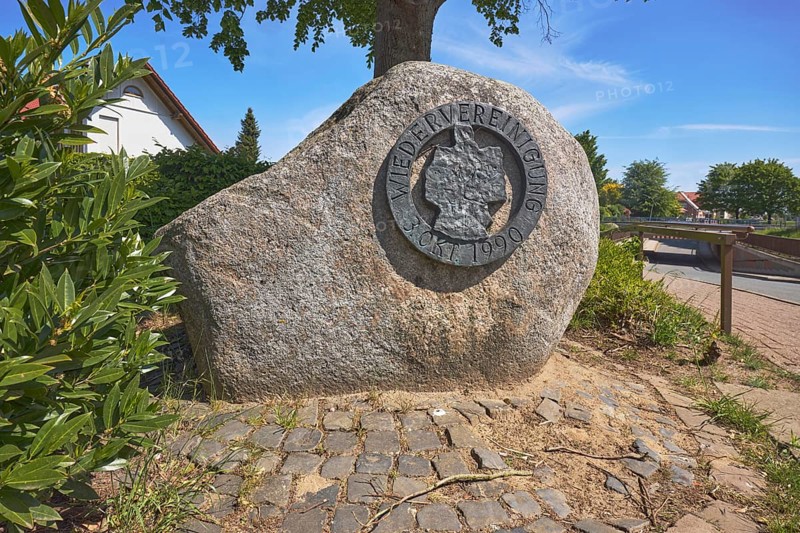 Monument, political event, reunification, flower bed, shrub, trees, cobblestone path, blue sky, cirrostratus clouds, Alte Schulstraße, Alfhausen, district of Osnabrück, Lower Saxony, Germany