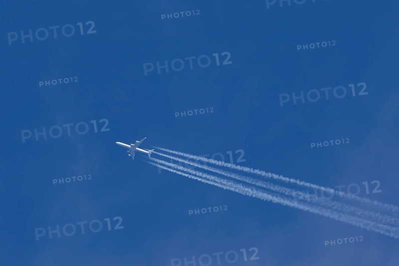 Airbus A340-300 jet aircraft of Lufthansa airlines in flight in a blue sky with vapour trails or contrails behind, England, United Kingdom