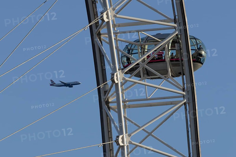 Airbus A320-232 jet passenger aircraft of British Airways airlines in flight in a blue sky with the London Eye wheel in the foreground, London, England, United Kingdom