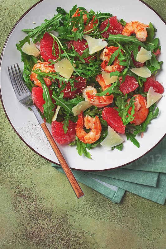 Fresh shrimp salad with arugula, grapefruit, and parmesan served in a bowl