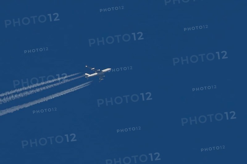 Boeing 747 Jumbo jet cargo aircraft in flight in a blue sky with vapour trails or contrails behind, England, United Kingdom