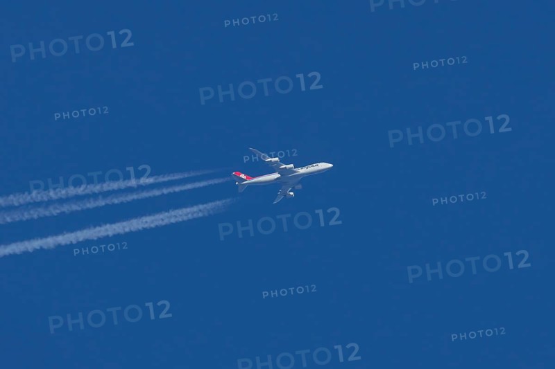 Boeing 747 Jumbo jet cargo aircraft of Cargolux airlines in flight in a blue sky with vapour trails or contrails behind, England, United Kingdom
