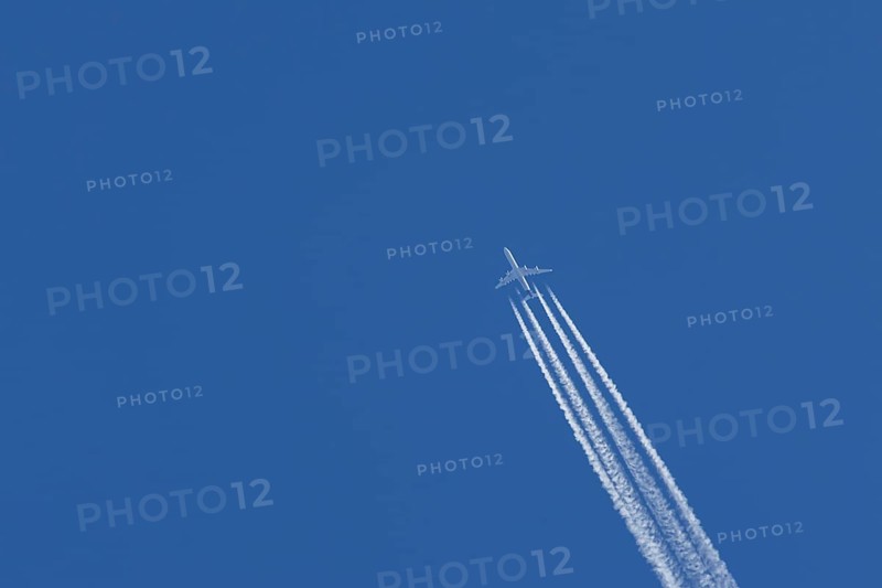 Airbus A340-300 jet aircraft of Lufthansa airlines in flight in a blue sky with vapour trails or contrails behind, England, United Kingdom