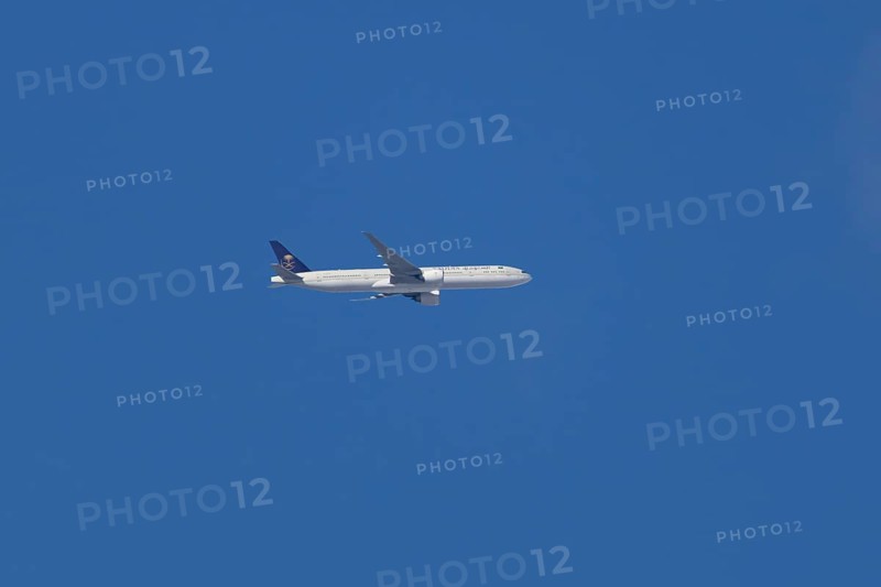 Boeing 777 jet passenger aircraft of Saudi airlines in flight in a blue sky, England, United Kingdom