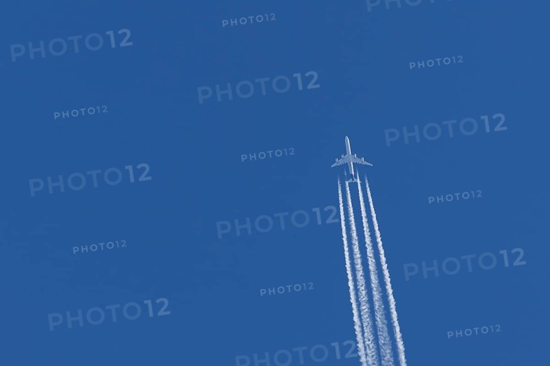 Airbus A340-300 jet aircraft of Lufthansa airlines in flight in a blue sky with vapour trails or contrails behind, England, United Kingdom