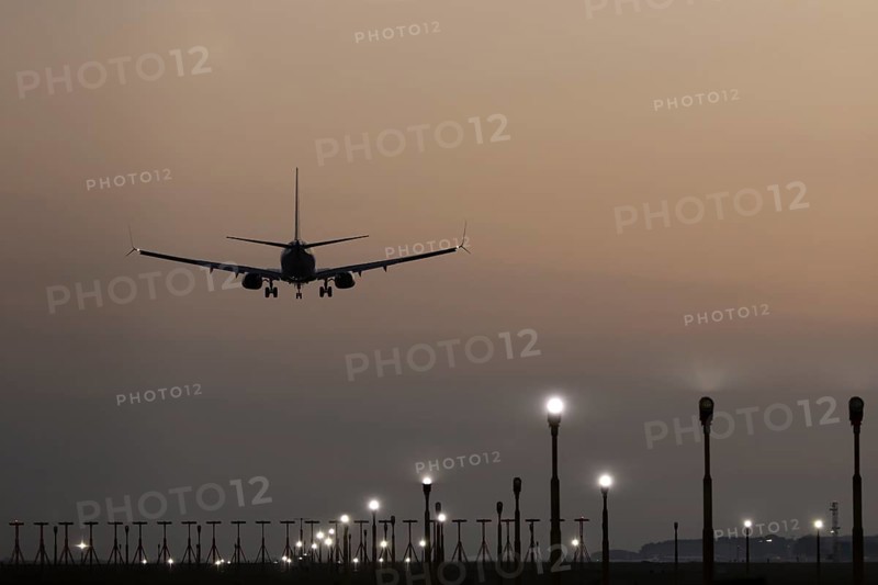 Boeing 737 jet passenger aircraft of Ryanair airlines landing over runway lights at sunset, London Stansted airport, Essex, England, United Kingdom
