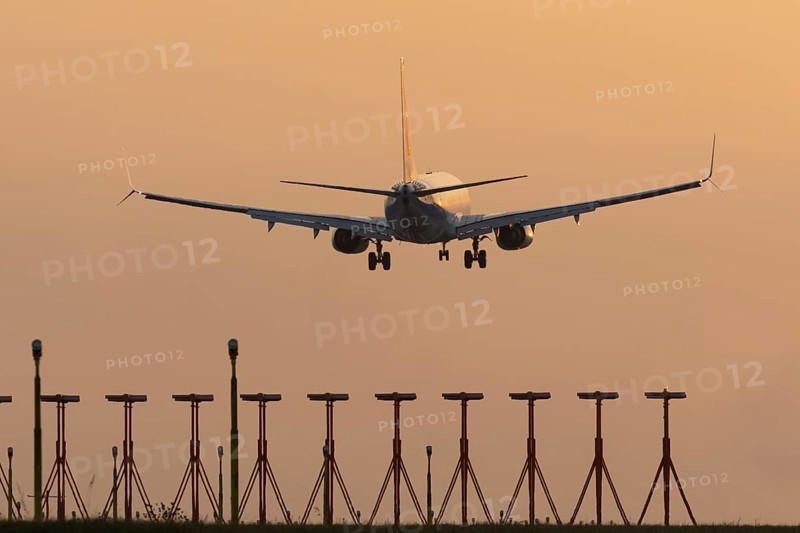 Boeing 737 jet passenger aircraft of Ryanair airlines landing over runway lights at sunset, London Stansted airport, Essex, England, United Kingdom