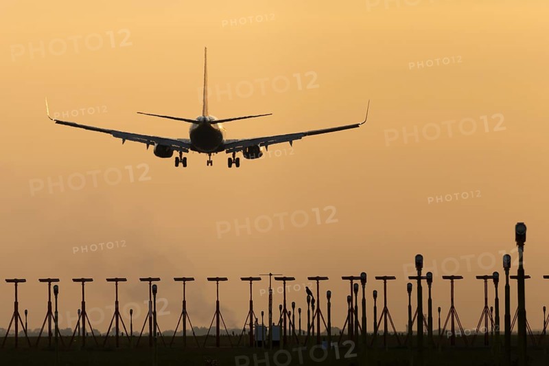 Boeing 737 jet passenger aircraft of Ryanair airlines landing over runway lights at sunset, London Stansted airport, Essex, England, United Kingdom