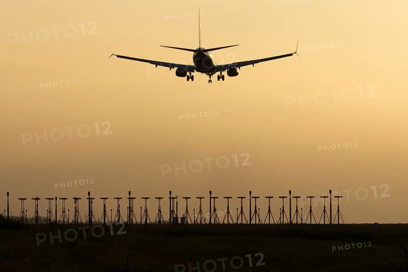 Boeing 737 jet passenger aircraft of Ryanair airlines landing over runway lights at sunset, London Stansted airport, Essex, England, United Kingdom