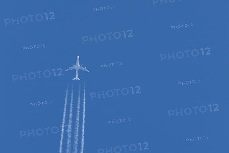 Airbus A340-300 jet aircraft of Lufthansa airlines in flight in a blue sky with vapour trails or contrails behind, England, United Kingdom