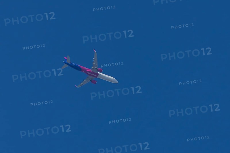 Airbus A321 jet aircraft of Wizz Air airlines in flight in a blue sky, England, United Kingdom