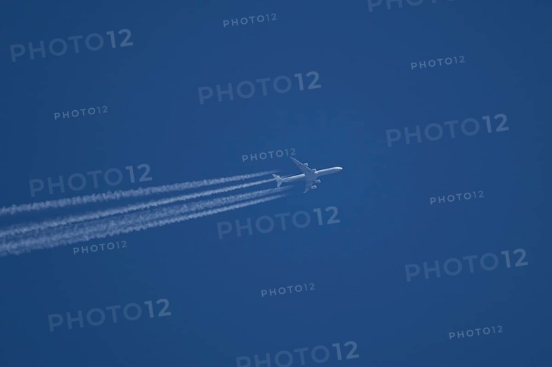 Airbus A340-300 jet aircraft of Lufthansa airlines in flight in a blue sky with vapour trails or contrails behind, England, United Kingdom