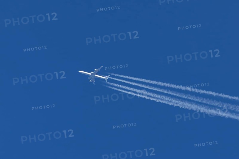 Airbus A340-300 jet aircraft of Lufthansa airlines in flight in a blue sky with vapour trails or contrails behind, England, United Kingdom