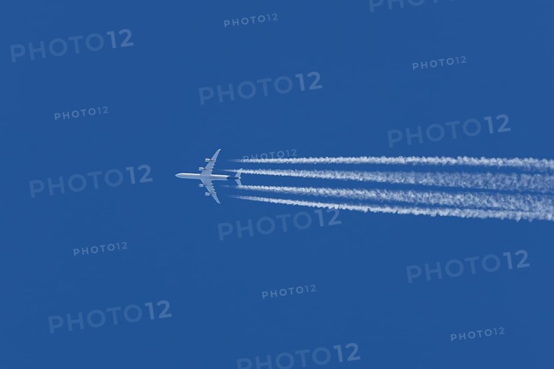Airbus A340-300 jet aircraft of Lufthansa airlines in flight in a blue sky with vapour trails or contrails behind, England, United Kingdom