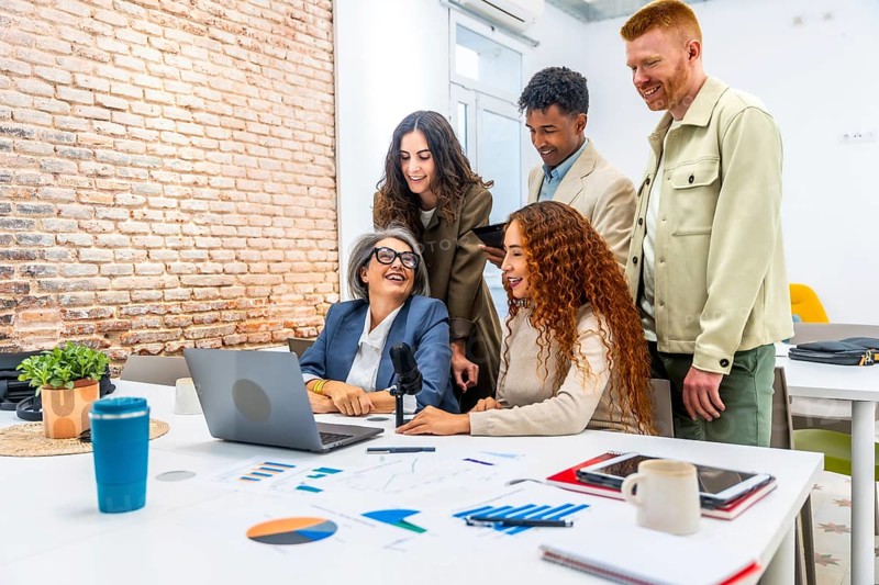 Diverse business professionals sharing ideas and laughing together during a collaborative podcast recording session or team meeting in a modern office space
