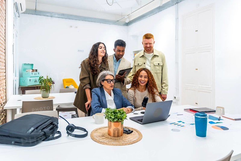 Diverse business team recording a podcast in a modern office, collaborating on content creation, brainstorming ideas, and using laptops and microphones for digital media production