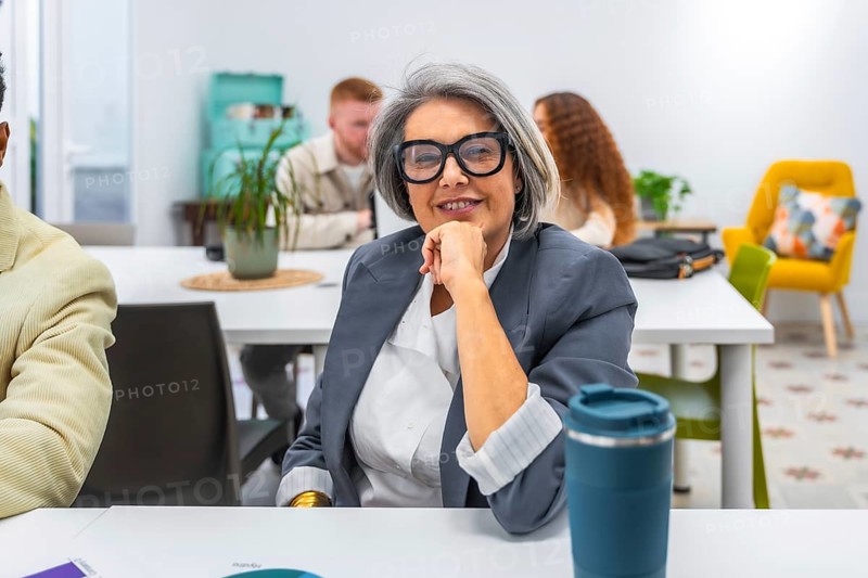Experienced senior businesswoman smiling confidently during a meeting in a modern office, representing professionalism, leadership, and successful collaboration among diverse team members