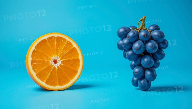 A halved orange and a bunch of dark blue grapes are set against a bright, solid blue backdrop, creating a striking contrast, AI generated