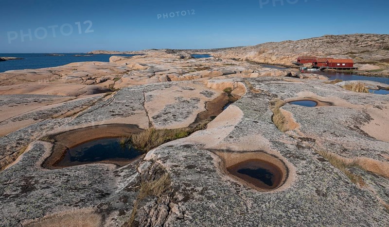 Rocks with rainwater puddles, falun red houses, rocky coast, Bohus granite, Ramsvik, nature reserve Ramsviklandet, Bohuslän, Skagerrak, Sotenäs, Västra Götalands län, Sweden