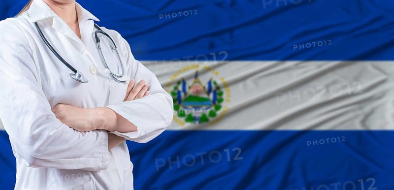 Doctor with crossed arms on El Salvador flag. El Salvador health and care concept. Female doctor on El Salvador flag