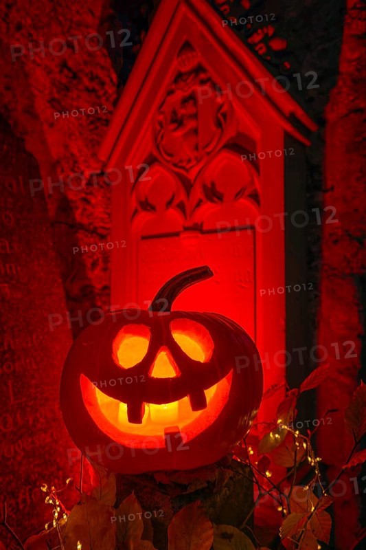 Halloween pumpkin with candlelight in the cemetery, illuminated red and spooky