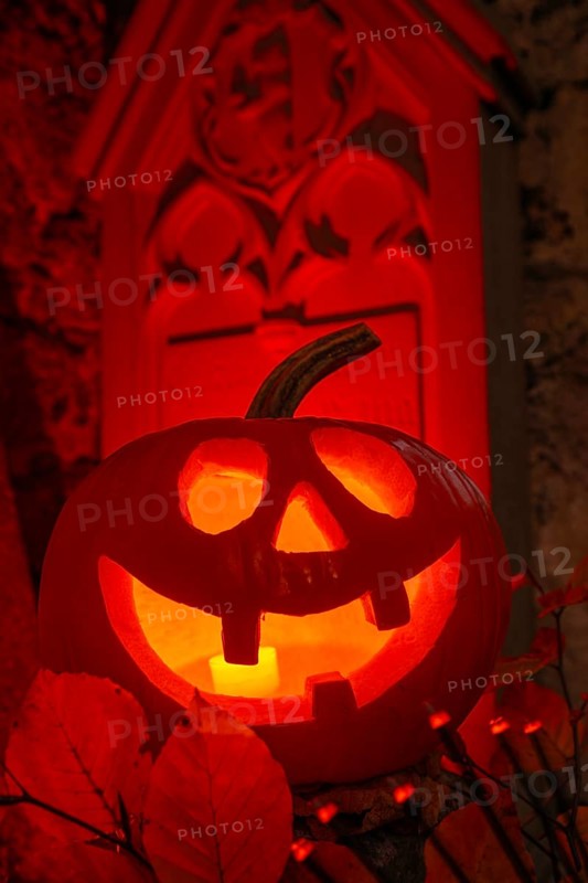 Halloween pumpkin with candlelight in the cemetery, illuminated red and spooky
