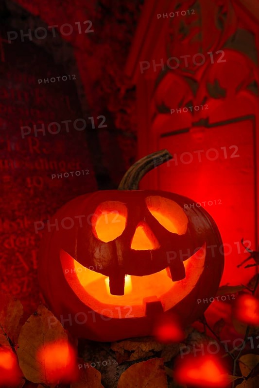 Halloween pumpkin with candlelight in the cemetery, illuminated red and spooky